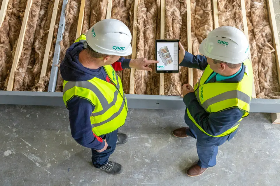 Dos trabajadores con casco revisando información en una tablet