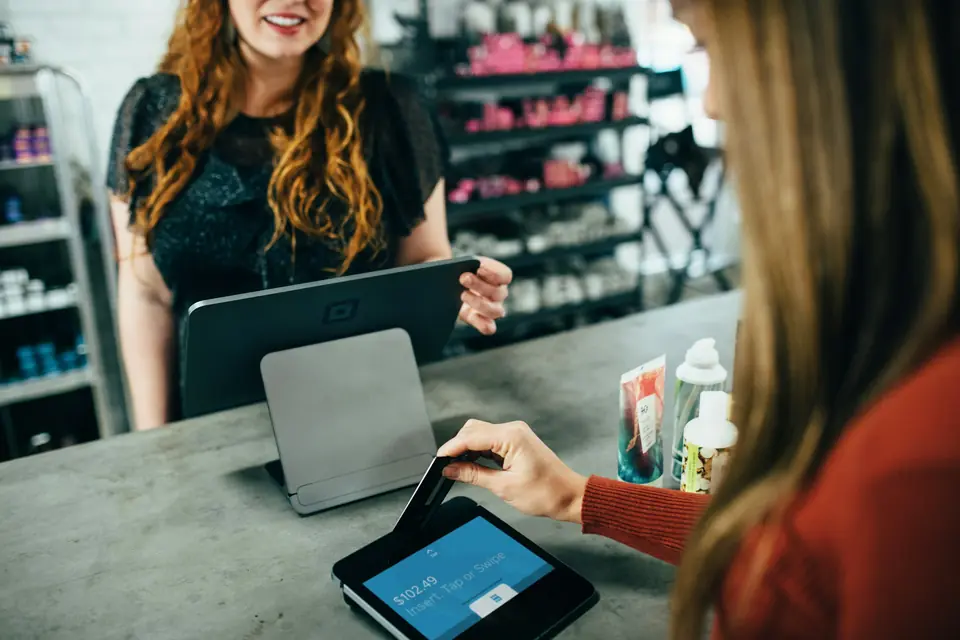 Clienta pagando en el mesón de una tienda con una caja en tablet