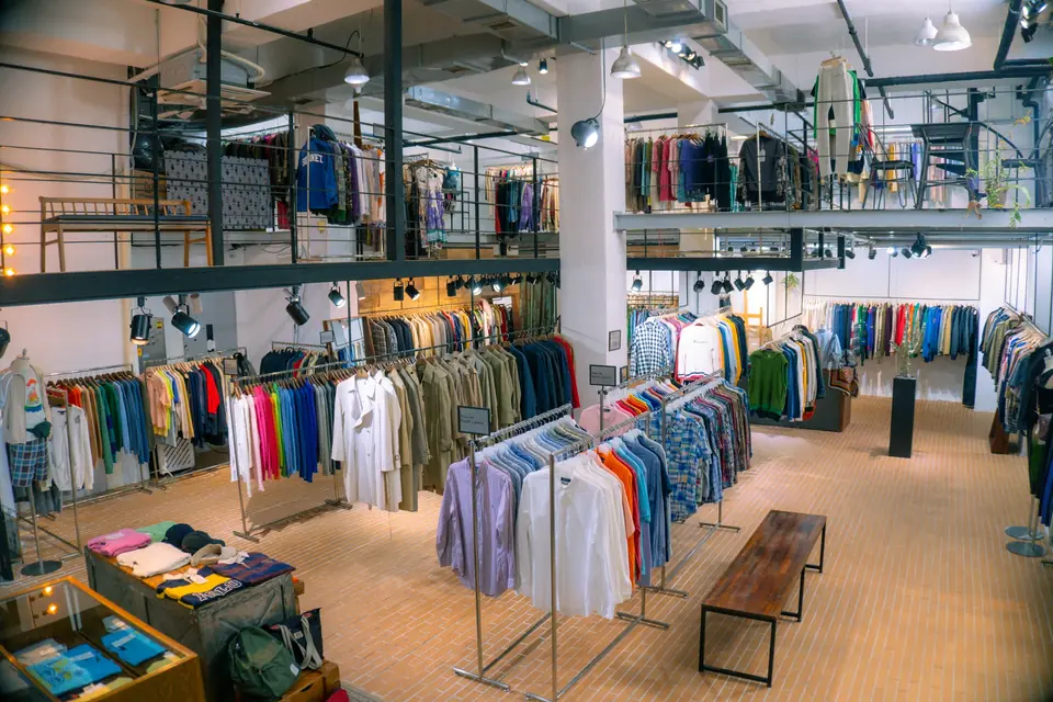 Interior de una tienda de ropa con percheros y mesas de exhibición